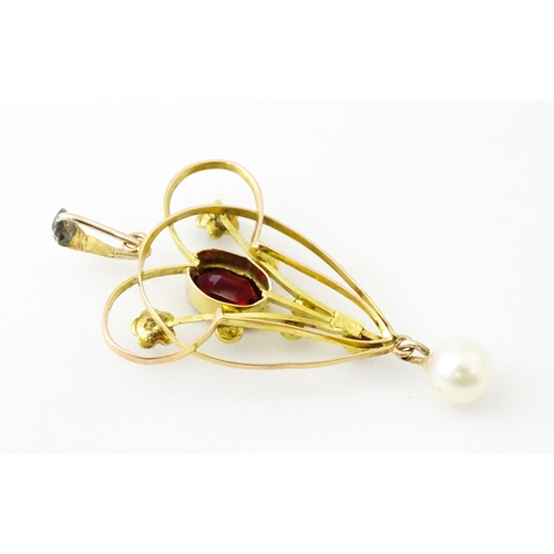 664 - A 9ct gold pendant in the Art Nouveau style set with central garnet flanked by seed pearls with pear... 