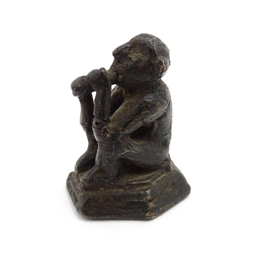 1010 - An Oriental cast model of a seated monkey, possibly a scroll weight. Together with a 20thC brass mat... 