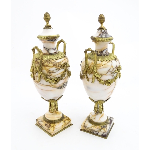 1223 - A pair of marble urns of pedestal form with gilt metal swag and bow mounts, twin handles and acanthu... 