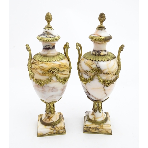 1223 - A pair of marble urns of pedestal form with gilt metal swag and bow mounts, twin handles and acanthu... 