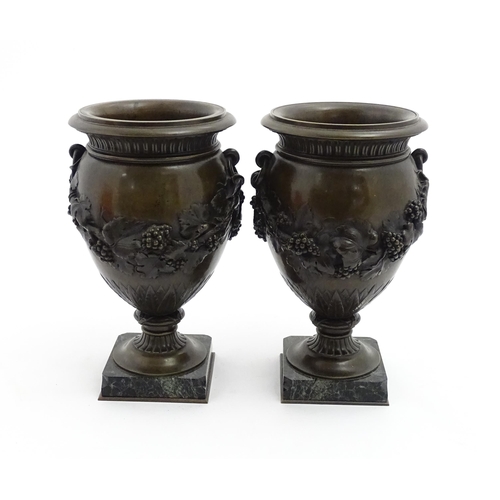 1225 - A pair cast pedestal urns with twin handles and relief fruiting vine decoration, raised on a marble ... 