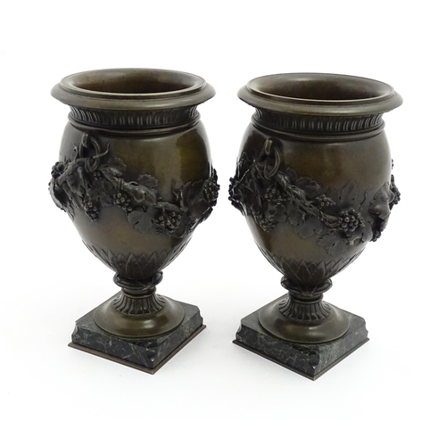 1225 - A pair cast pedestal urns with twin handles and relief fruiting vine decoration, raised on a marble ... 