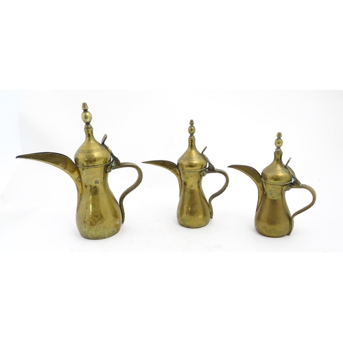 1253 - Three Middle Eastern brass graduated Dallah coffee pots. Largest approx. 14 3/4