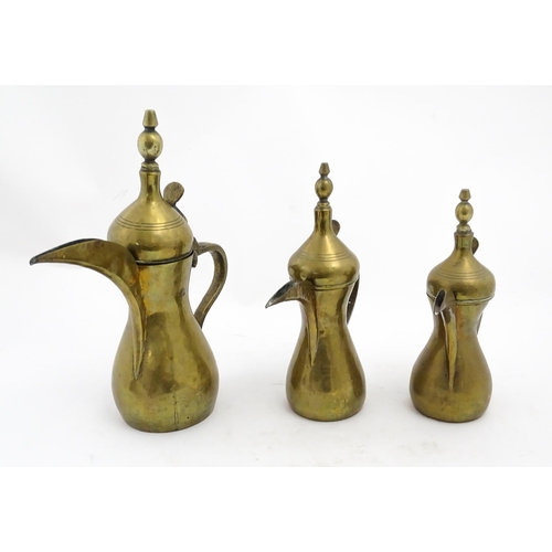 1253 - Three Middle Eastern brass graduated Dallah coffee pots. Largest approx. 14 3/4