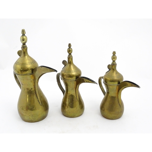 1253 - Three Middle Eastern brass graduated Dallah coffee pots. Largest approx. 14 3/4