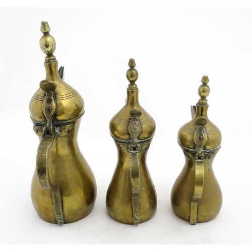 1253 - Three Middle Eastern brass graduated Dallah coffee pots. Largest approx. 14 3/4