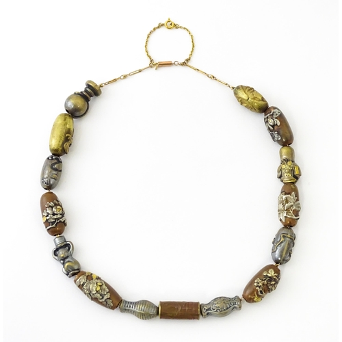 670 - A yellow metal necklace set with 15 Japanese ojime beads, with various decoration to include floral ... 