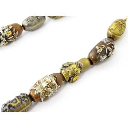 670 - A yellow metal necklace set with 15 Japanese ojime beads, with various decoration to include floral ... 