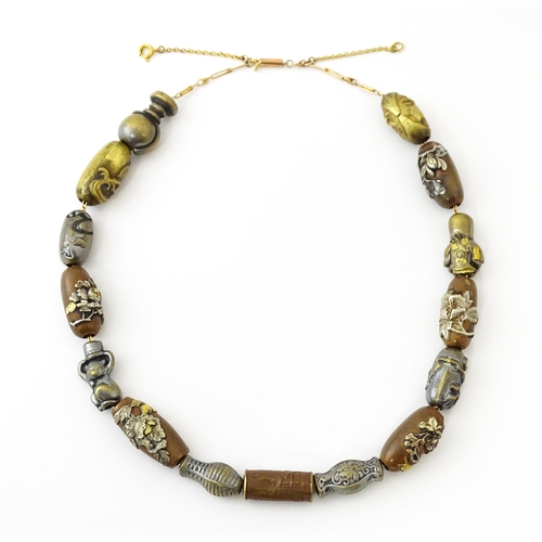 670 - A yellow metal necklace set with 15 Japanese ojime beads, with various decoration to include floral ... 