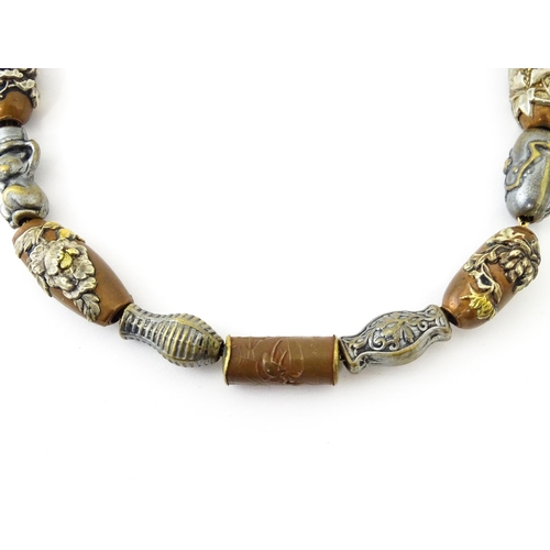 670 - A yellow metal necklace set with 15 Japanese ojime beads, with various decoration to include floral ... 