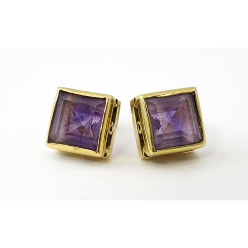 673 - A pair of yellow metal stud earrings of squared form set with amethyst. Approx. 1/4