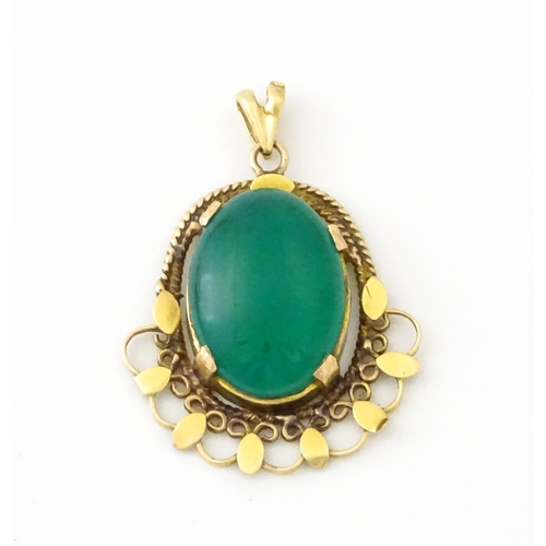 674 - A yellow metal pendant set with central green cabochon. Approx. 1 1/4