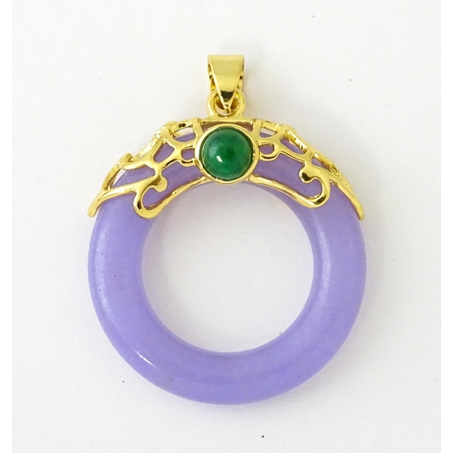 677 - A pendant with gilt metal mounts and purple coloured jade like ring detail. 1 1/2