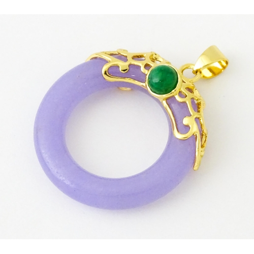 677 - A pendant with gilt metal mounts and purple coloured jade like ring detail. 1 1/2