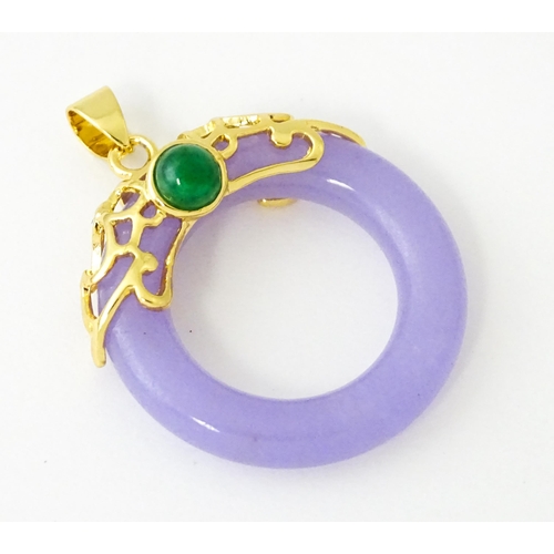 677 - A pendant with gilt metal mounts and purple coloured jade like ring detail. 1 1/2