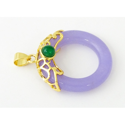 677 - A pendant with gilt metal mounts and purple coloured jade like ring detail. 1 1/2