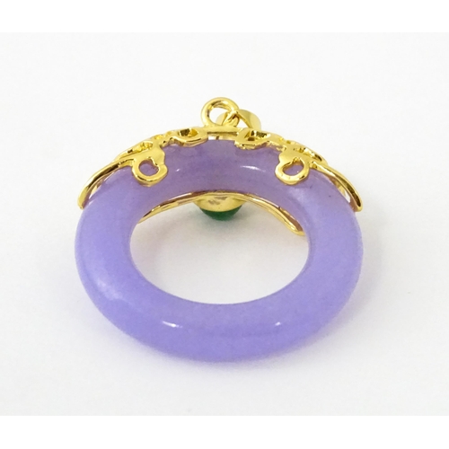 677 - A pendant with gilt metal mounts and purple coloured jade like ring detail. 1 1/2