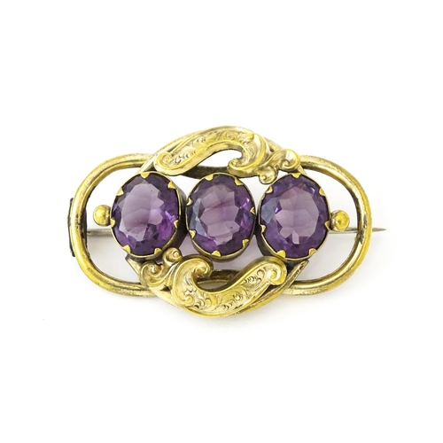 680 - A gilt metal brooch set with three purple coloured stones. Approx. 2