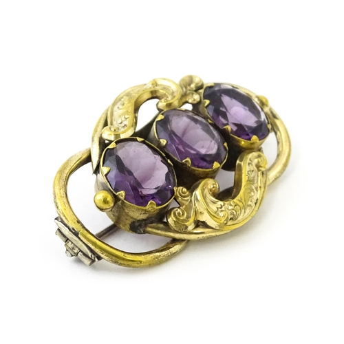 680 - A gilt metal brooch set with three purple coloured stones. Approx. 2