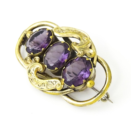 680 - A gilt metal brooch set with three purple coloured stones. Approx. 2