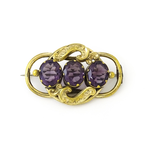 680 - A gilt metal brooch set with three purple coloured stones. Approx. 2