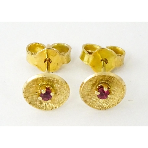 696 - A pair of yellow metal stud earrings set with red stones to centre. Approx. 1/4