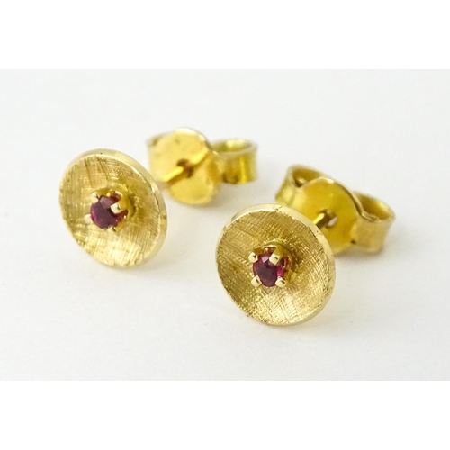 696 - A pair of yellow metal stud earrings set with red stones to centre. Approx. 1/4