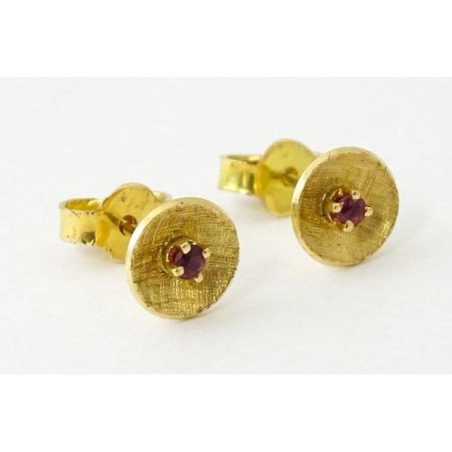 696 - A pair of yellow metal stud earrings set with red stones to centre. Approx. 1/4