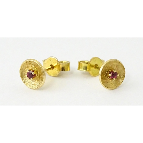 696 - A pair of yellow metal stud earrings set with red stones to centre. Approx. 1/4