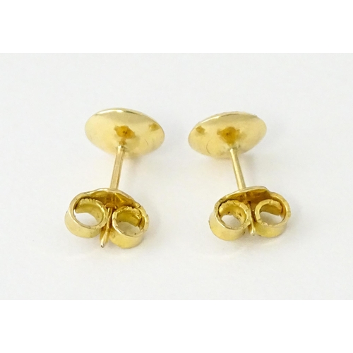 696 - A pair of yellow metal stud earrings set with red stones to centre. Approx. 1/4