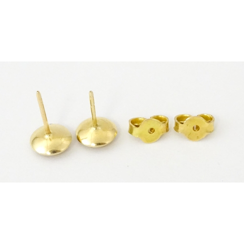 696 - A pair of yellow metal stud earrings set with red stones to centre. Approx. 1/4