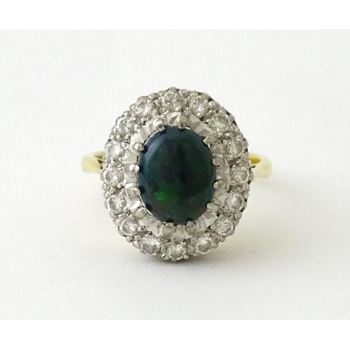 701 - An 18ct gold ring set with central opal bordered by diamonds. Ring size approx. L 1/2