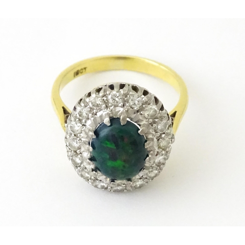 701 - An 18ct gold ring set with central opal bordered by diamonds. Ring size approx. L 1/2