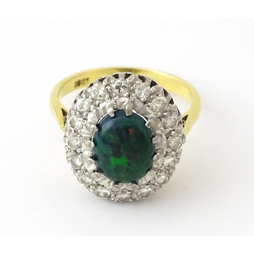 701 - An 18ct gold ring set with central opal bordered by diamonds. Ring size approx. L 1/2