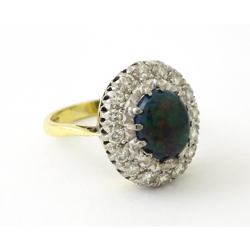 701 - An 18ct gold ring set with central opal bordered by diamonds. Ring size approx. L 1/2