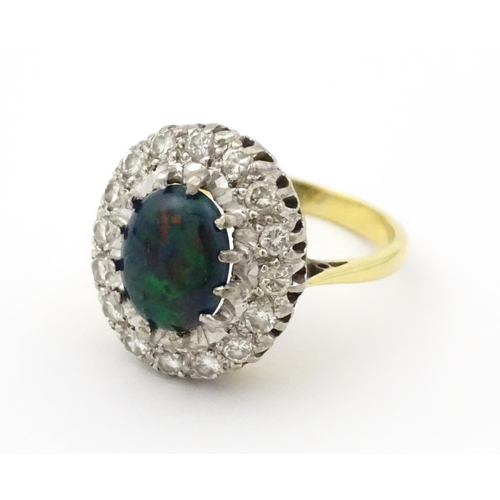 701 - An 18ct gold ring set with central opal bordered by diamonds. Ring size approx. L 1/2