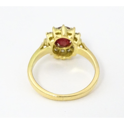 706 - An 18ct gold ring set with central ruby bordered by diamonds. Ring size approx. H 1/2