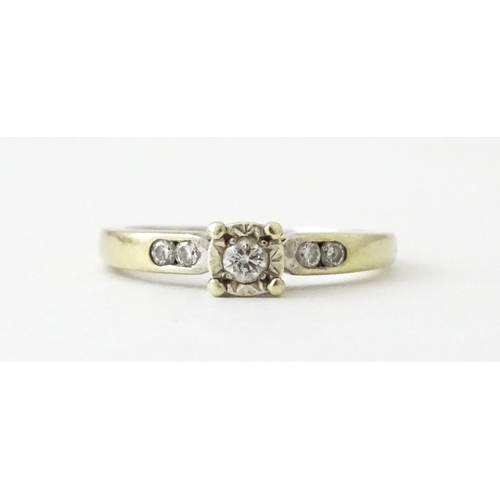 713 - A 9ct gold ring set with a central diamond flanked by further diamonds. Ring size approx. I