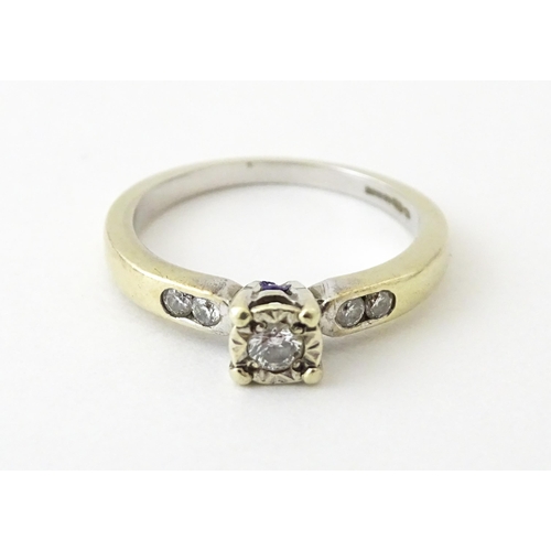 713 - A 9ct gold ring set with a central diamond flanked by further diamonds. Ring size approx. I