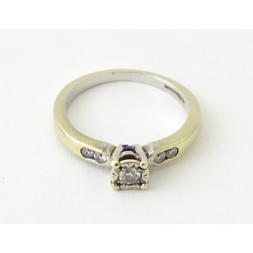 713 - A 9ct gold ring set with a central diamond flanked by further diamonds. Ring size approx. I