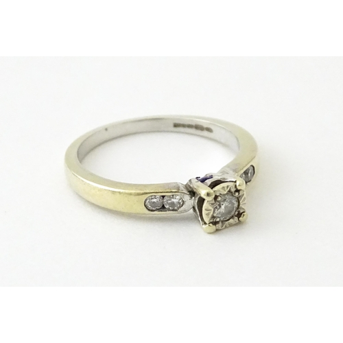 713 - A 9ct gold ring set with a central diamond flanked by further diamonds. Ring size approx. I