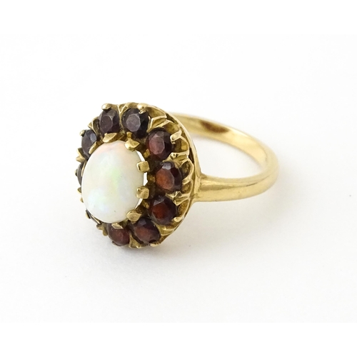 714 - A 9ct gold ring set with central opal bordered by garnets. Ring size approx. K 1/2