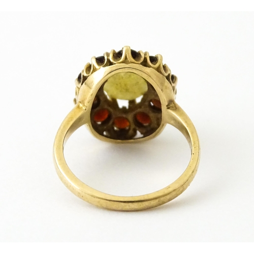 714 - A 9ct gold ring set with central opal bordered by garnets. Ring size approx. K 1/2