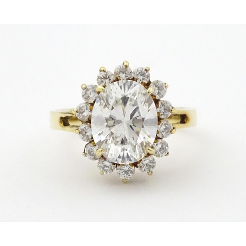 716 - A yellow metal dress ring set with central white stone bordered by further white stones. Ring size a... 