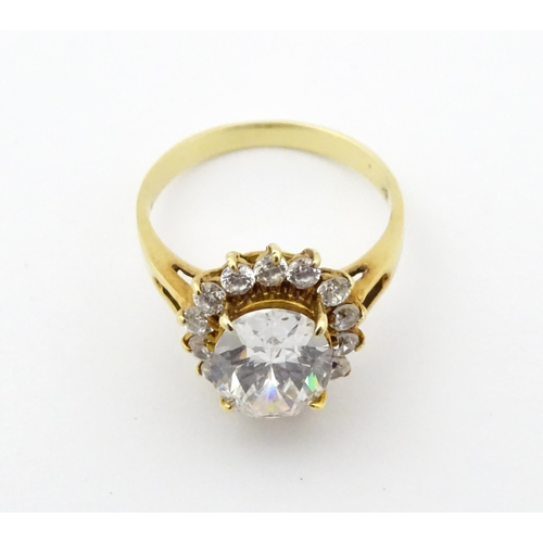 716 - A yellow metal dress ring set with central white stone bordered by further white stones. Ring size a... 