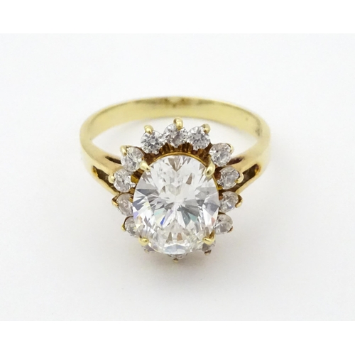 716 - A yellow metal dress ring set with central white stone bordered by further white stones. Ring size a... 