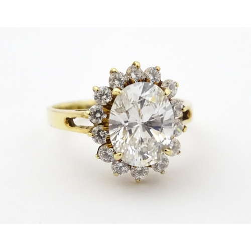 716 - A yellow metal dress ring set with central white stone bordered by further white stones. Ring size a... 