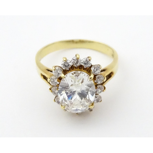 716 - A yellow metal dress ring set with central white stone bordered by further white stones. Ring size a... 