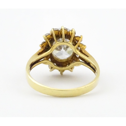 716 - A yellow metal dress ring set with central white stone bordered by further white stones. Ring size a... 