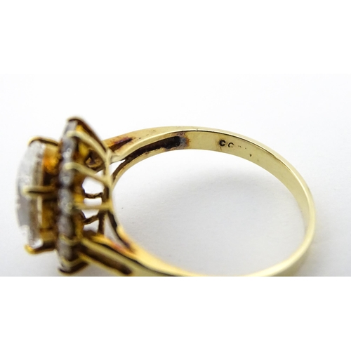 716 - A yellow metal dress ring set with central white stone bordered by further white stones. Ring size a... 